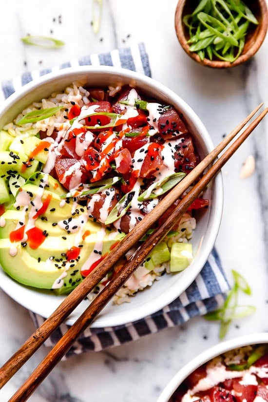 Spicy Tuna Poke Bowls made with chunks of fresh tuna, avocado, cucumbers, spicy mayo, scallions cut on the bias served on a bed of steamed rice.