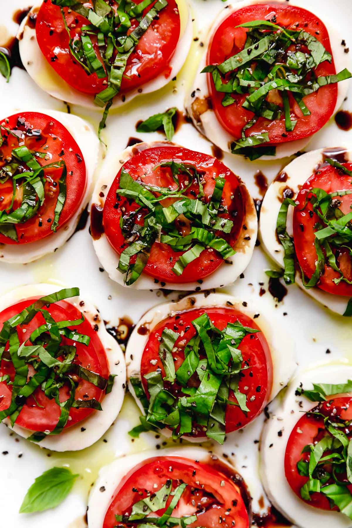 Caprese salad is a simple summer salad with fresh mozzarella, thick slices of juicy tomatoes, basil and a splash of balsamic vinegar. So easy! Overhead view of classic Caprese salad on platter