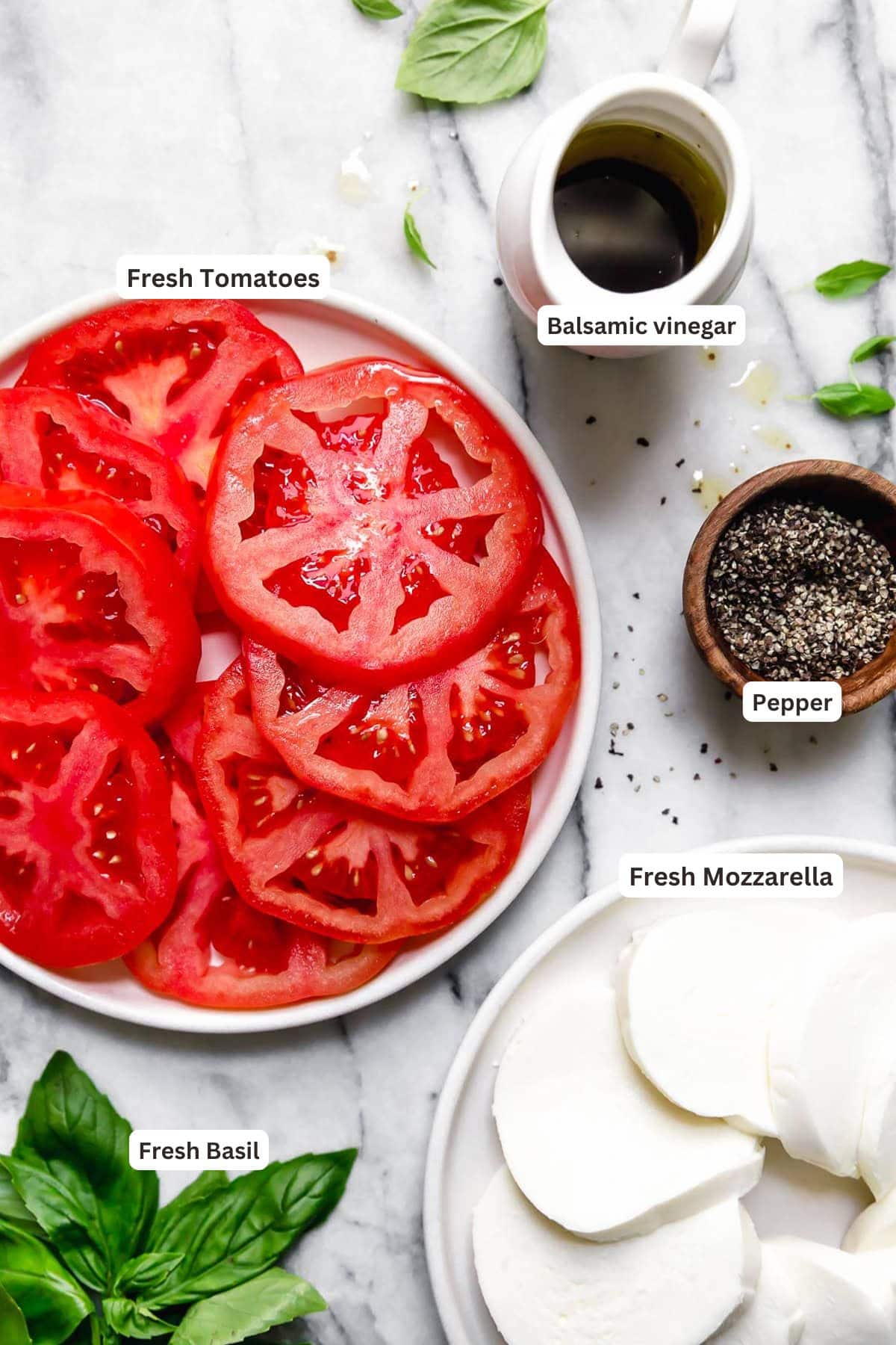 Ingredients for caprese salad on white plates.