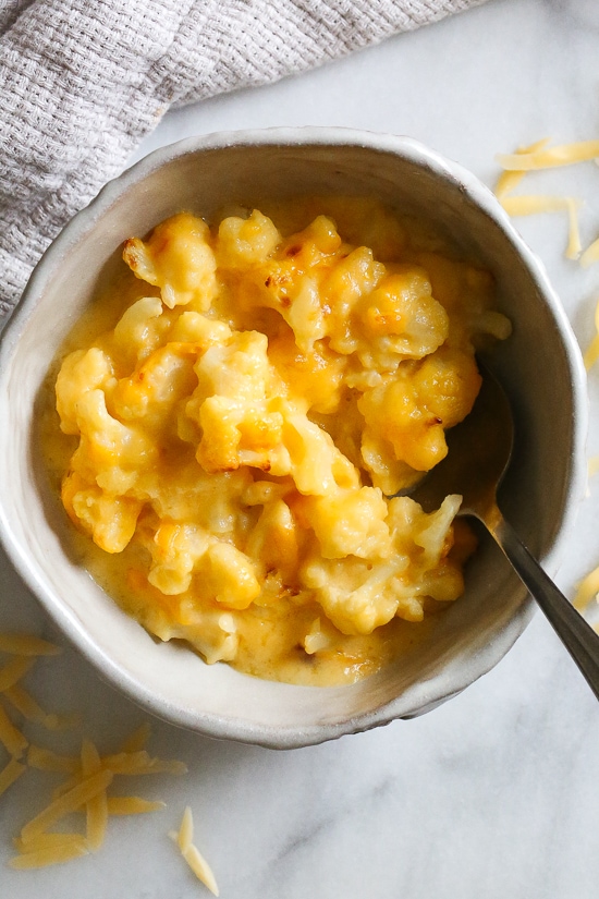 Cheesy Baked Cauliflower "Mac" and Cheese is perfect when you're craving macaroni and cheese–without the pasta! It's lower in carbs and each bowl has a healthy amount of vegetables and protein! Baked Cauliflower "Mac" and Cheese in a bowl.