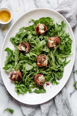 Prosciutto Wrapped Figs with Blue Cheese served on a bed of baby arugula with a light vinaigrette. A delicious combination of salt, acid and sweet.