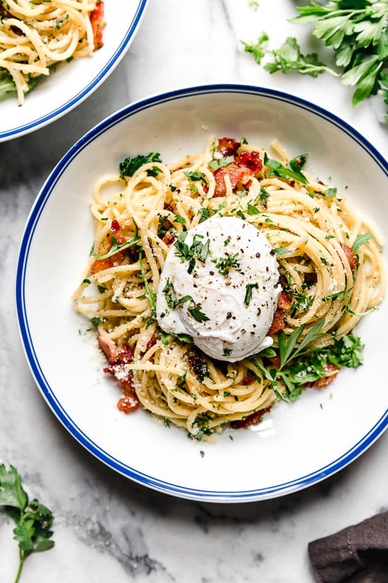 With diced bacon, grated cheese, black pepper, and a poached egg, this Spaghetti Carbonara is simple yet elegant. Overhead view of a bowl of spaghetti carbonara topped with a poached egg