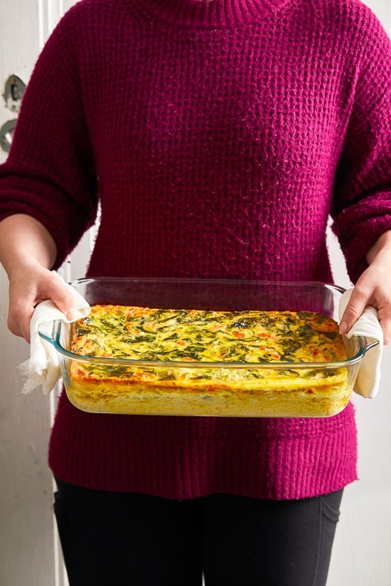This easy Breakfast Casserole recipe is made with eggs, spinach, tomatoes and Feta cheese and only takes a few minutes to whip up. You can make it ahead of time, so it’s the perfect breakfast egg casserole for Christmas morning or any day!