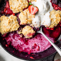 Skillet Mixed Berry Buttermilk Cobbler is made with blackberries, raspberries, and strawberries covered with a delicious biscuit topping and baked in a cast iron skillet.