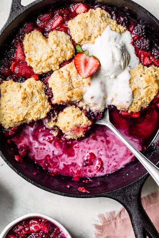 Skillet Mixed Berry Buttermilk Cobbler is made with blackberries, raspberries, and strawberries covered with a delicious biscuit topping and baked in a cast iron skillet.
