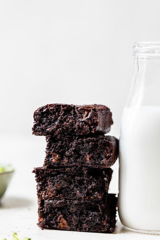 These easy Flourless Zucchini Brownies are made with almond meal, so they're naturally gluten-free. They're moist, fudgy, and so decadent! Stack of 4 Flourless Zucchini Brownies with a bottle of milk