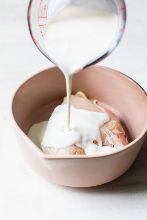 pouring buttermilk on chicken breast