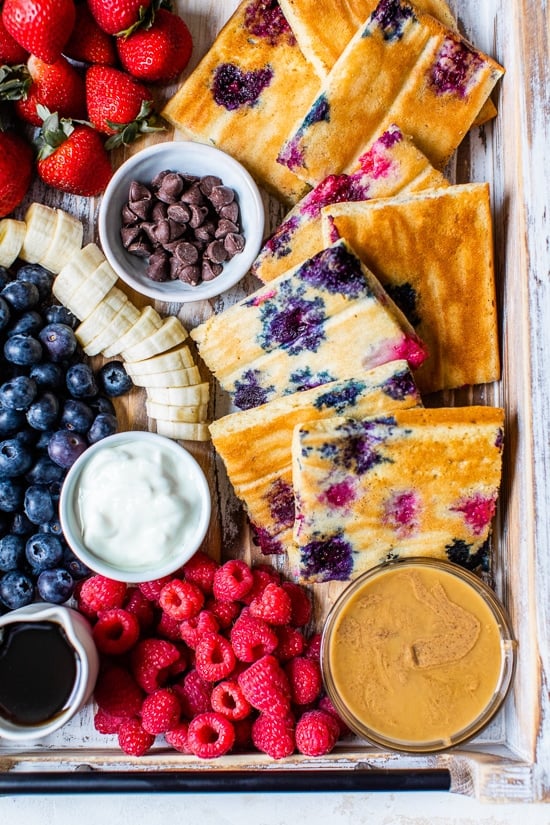 sheet pan pancakes on a try with berries and toppings.