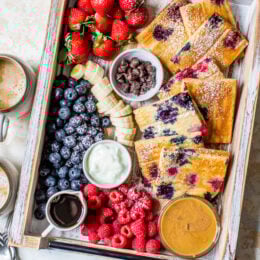 sheet pan pancakes on a try with berries and toppings.