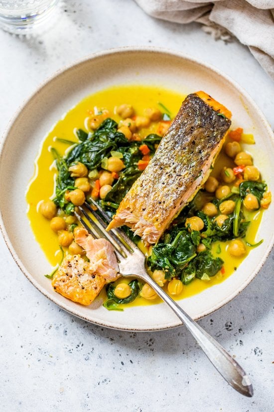 salmon on a plate with a fork, spinach and chickpeas