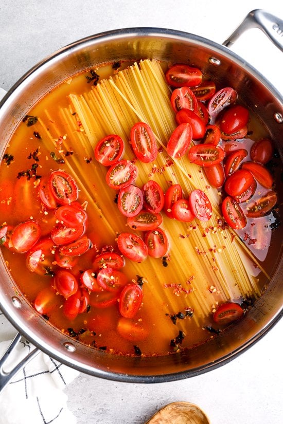 pasta tomatoes and water in a skillet before cooking