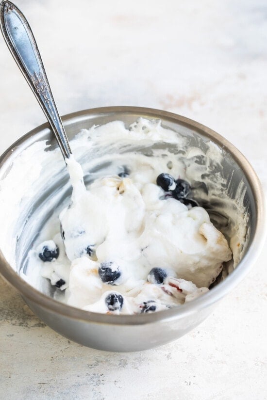 Mixing ambrosia salad in a metal bowl.