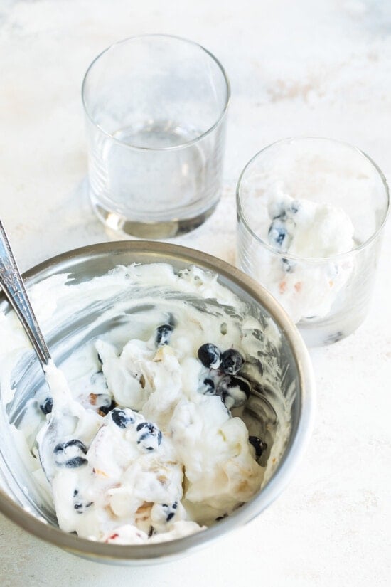 Dividing the Ambrosia Salad amongst glass containers.