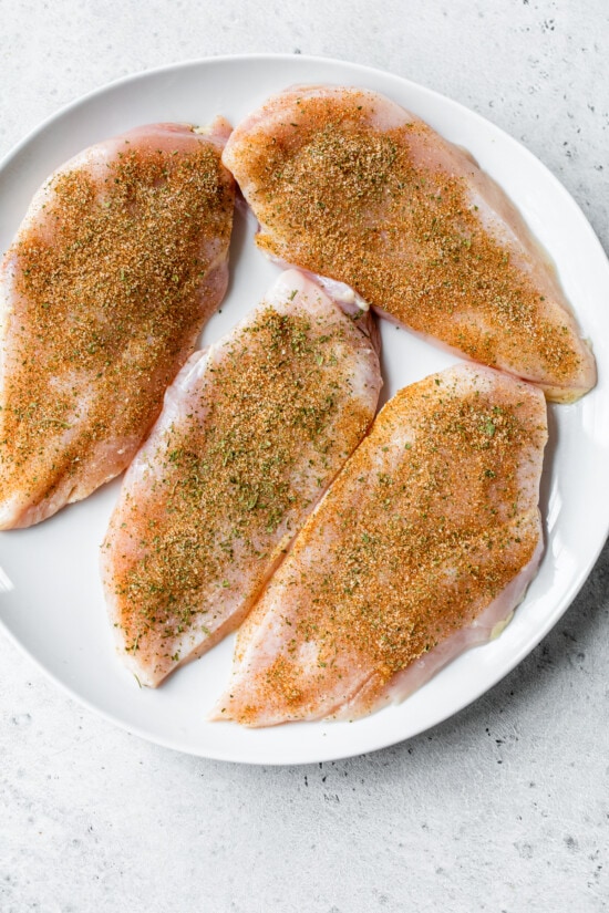 raw seasoned chicken breast on a plate