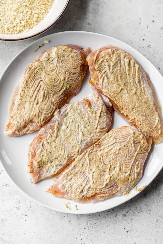 raw chicken breast with mayo and seasoning on top of it