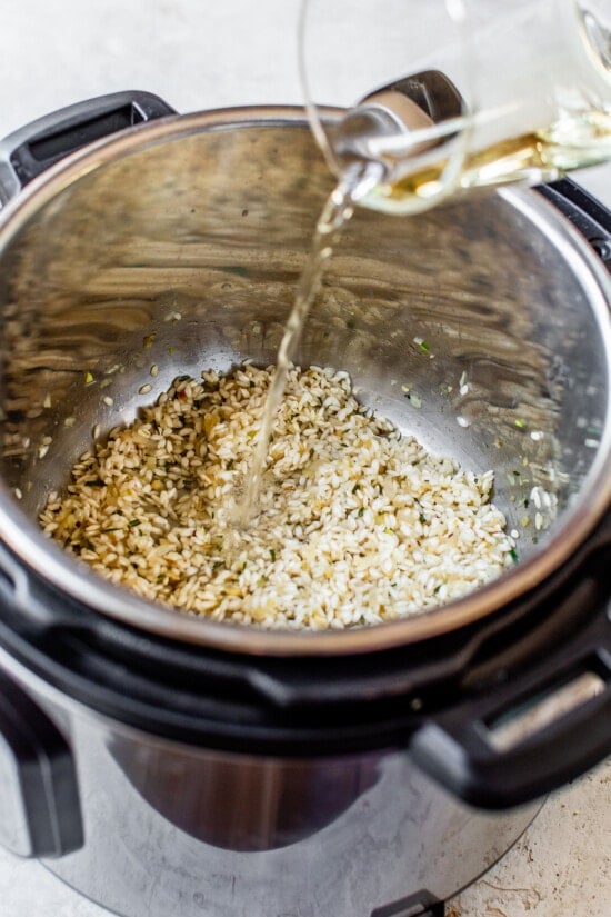 This Instant Pot Risotto recipe is the quickest, easiest way to make risotto. Perfectly creamy every time and it's ready in just 20 minutes. Broth being added to an Instant Pot with risotto