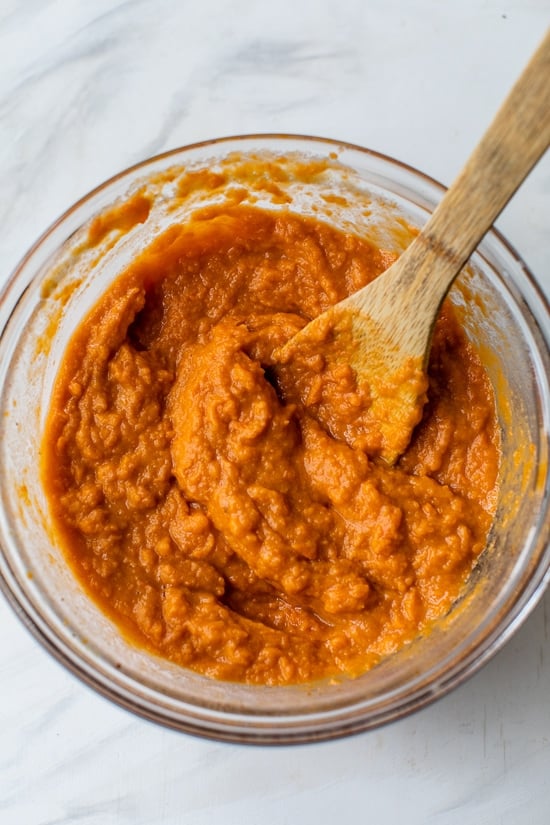 This lightened up Sweet Potato Casserole is made with roasted sweet potatoes and a praline topping for a crowd-pleasing Thanksgiving side! Stirring ingredients for sweet potato casserole in bowl.