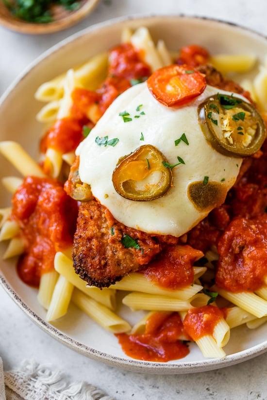 Spicy Vodka Chicken Parmesan is made with hot cherry peppers, vodka sauce, fresh mozzarella, and breaded chicken cutlets. Baked or air fryer! Chicken Parmesan with hot cherry peppers over pasta