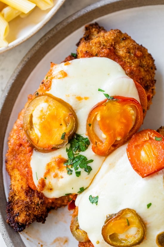 Spicy Vodka Chicken Parmesan is made with hot cherry peppers, vodka sauce, fresh mozzarella, and breaded chicken cutlets. Baked or air fryer! Spicy Vodka Chicken Parmesan on a plate