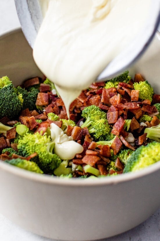 pouring dressing over broccoli salad