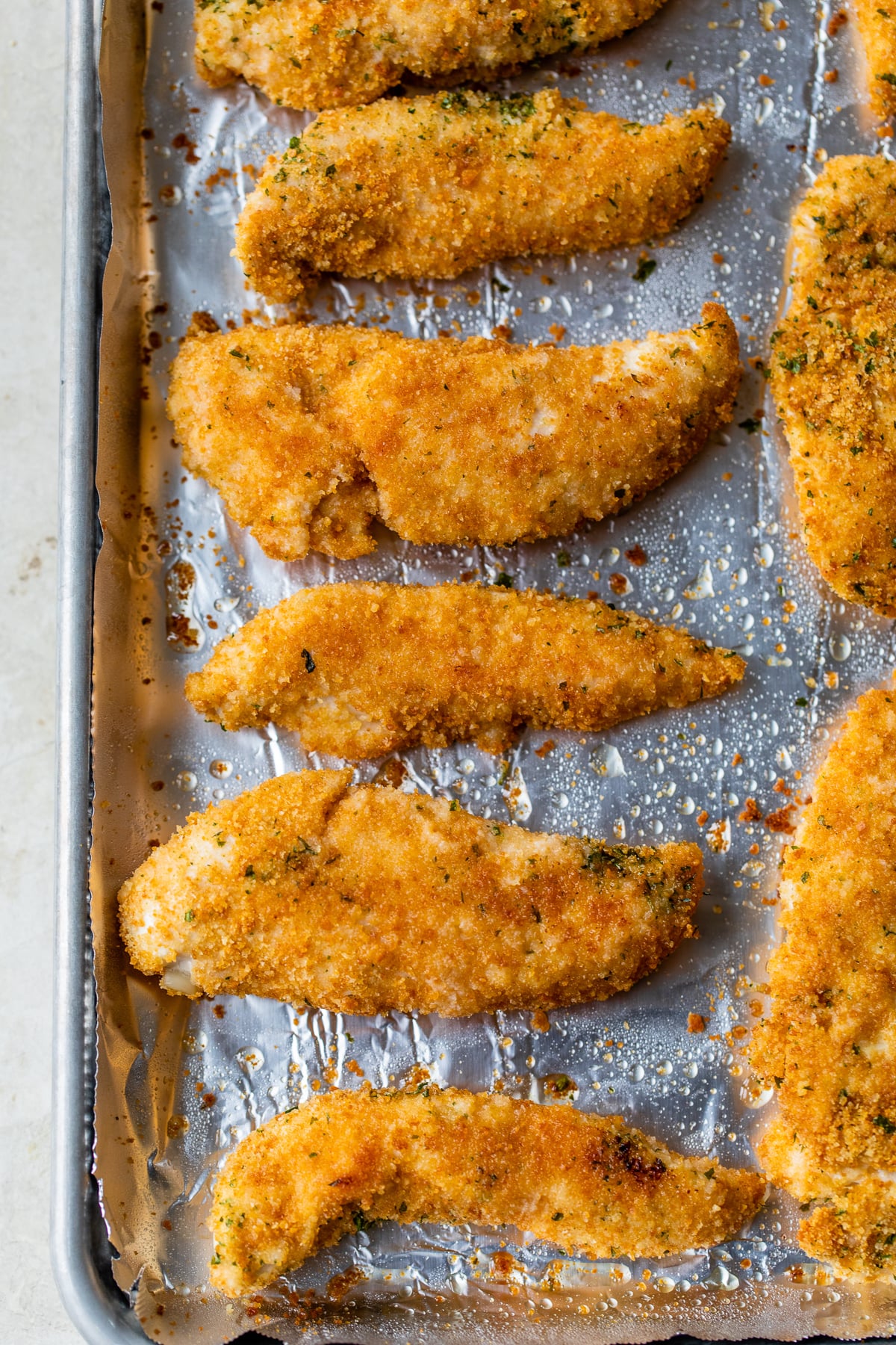 Quick and easy to prepare, this Baked Chicken Tenderloin Parmesan is a family-friendly weeknight dish, prepared with just a few ingredients. Baked chicken tenderloins on a baking sheet