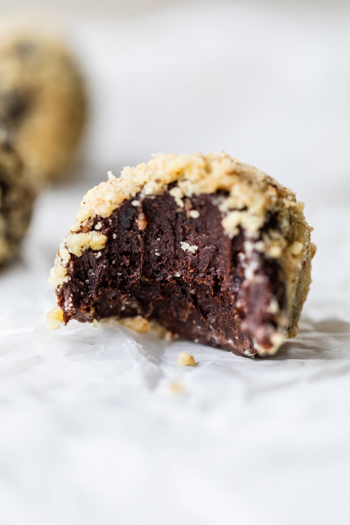Made with Medjool dates, pumpkin, and cocoa powder, these Chocolate Date Balls taste just like a brownie! No bake & easy! Close up of a chocolate ball to show the fudgy inside
