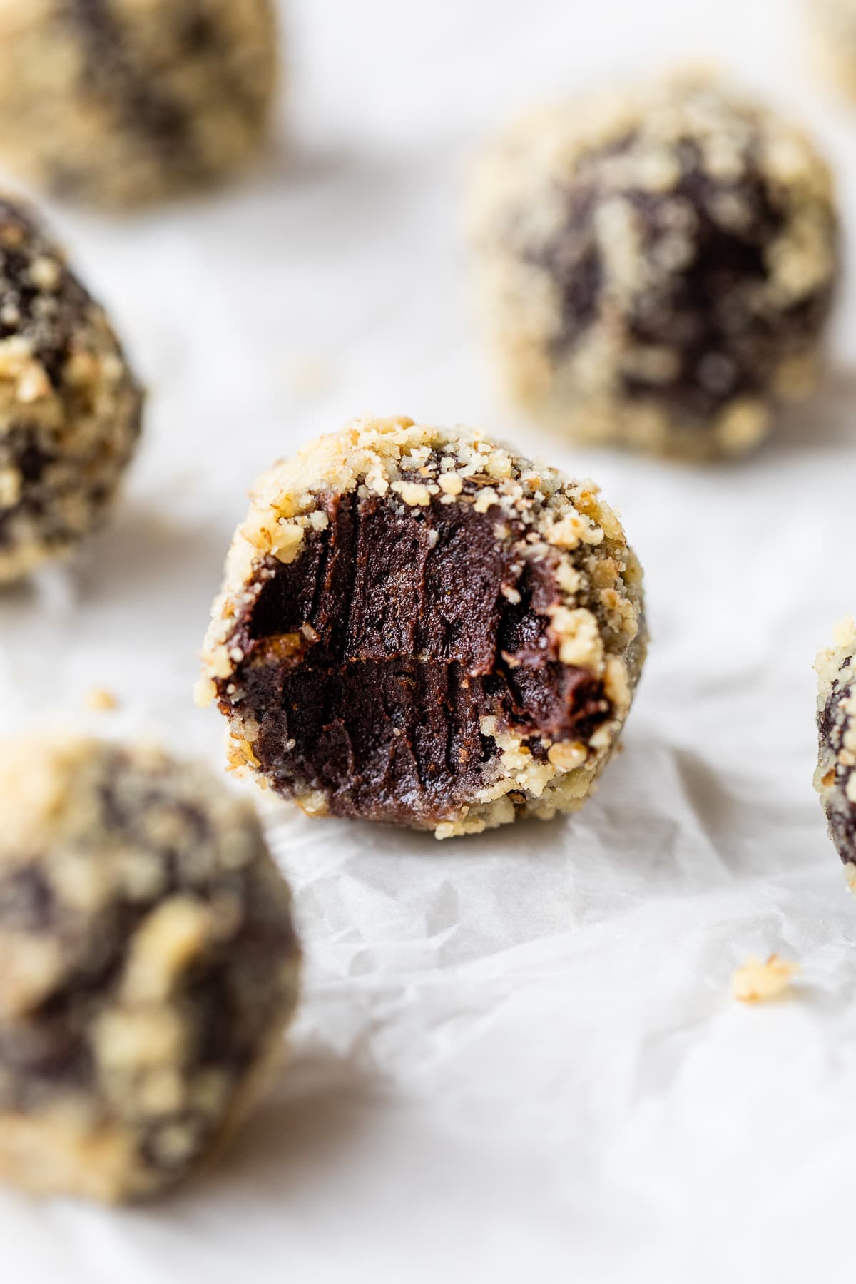 Made with Medjool dates, pumpkin, and cocoa powder, these Chocolate Date Balls taste just like a brownie! No bake & easy! A chocolate date ball with a bite missing to show the fudgy interior