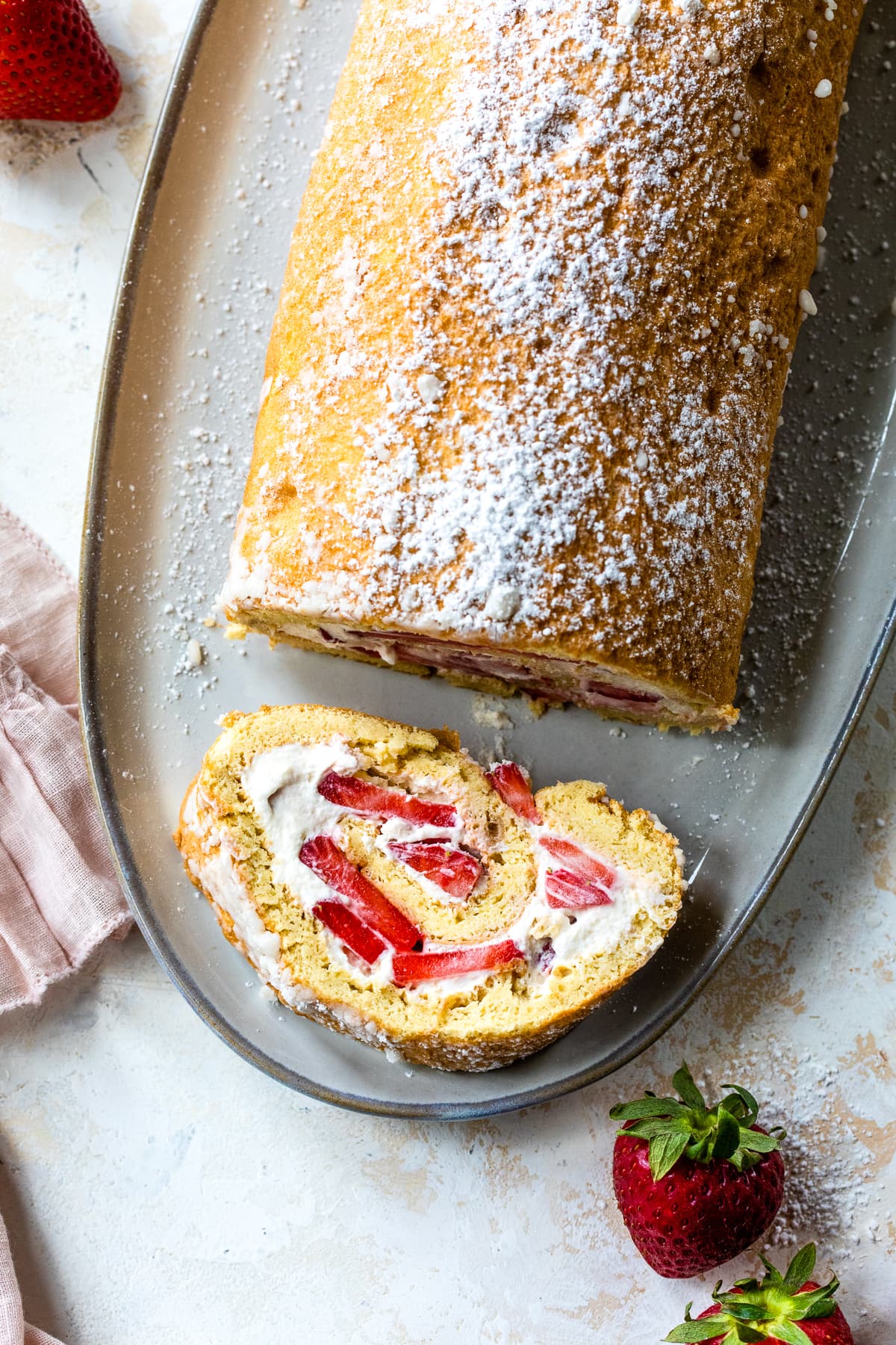 This Strawberry Swiss Roll features a soft sponge cake, sweet cream, and fresh strawberries. So simple & perfect when berries are in season. Strawberry Swiss Roll with a slice taken out.