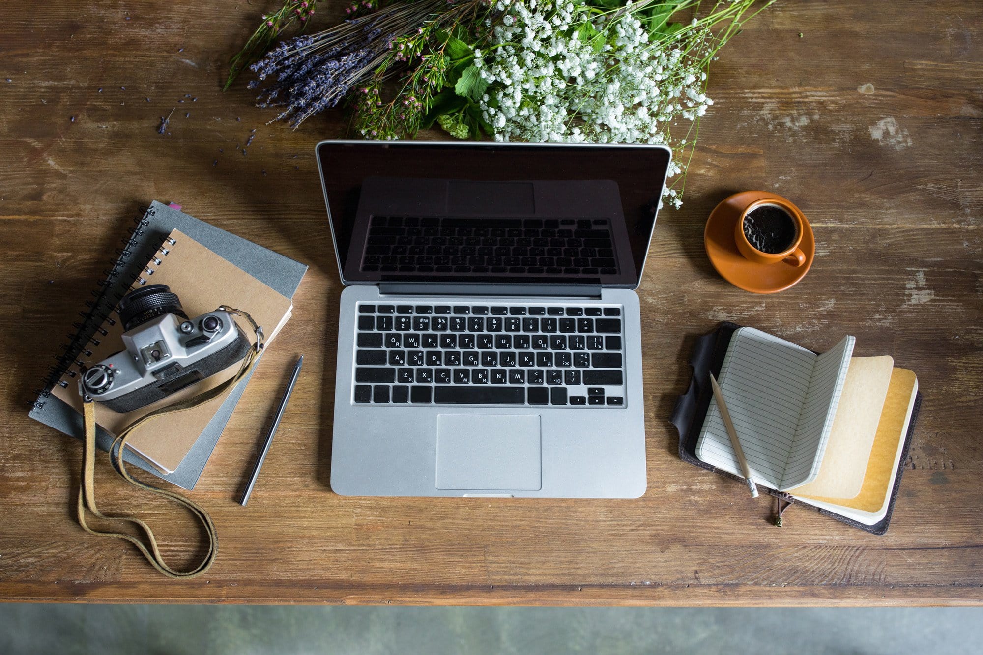 top view of best freelance jobs laptop, diaries, vintage photo camera and cup of coffee on wooden tabletop
