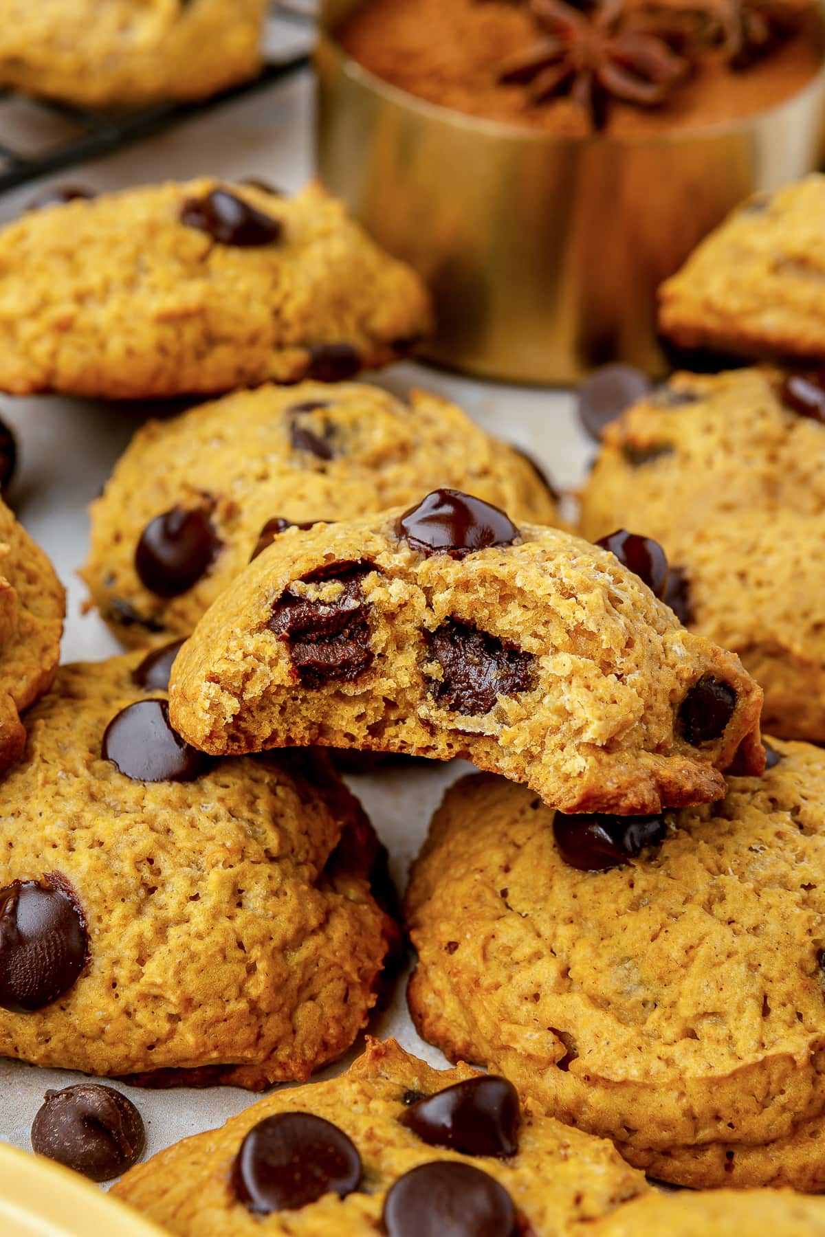  Pumpkin Chocolate Chip Cookies on a cookie sheet, one with a bite missing