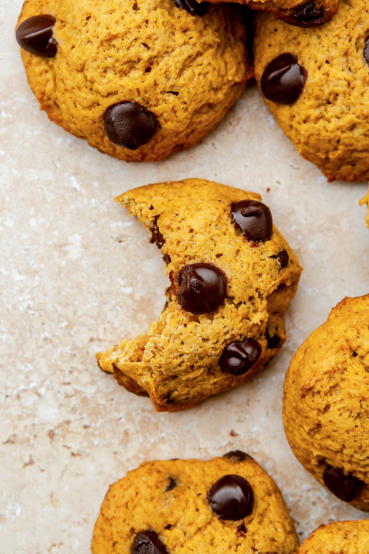 Soft Pumpkin Chocolate Chip Cookies, made with pumpkin puree, pumpkin spice, and cream cheese, have a cake-like texture and pumpkin flavor! half eaten pumpkin cookie