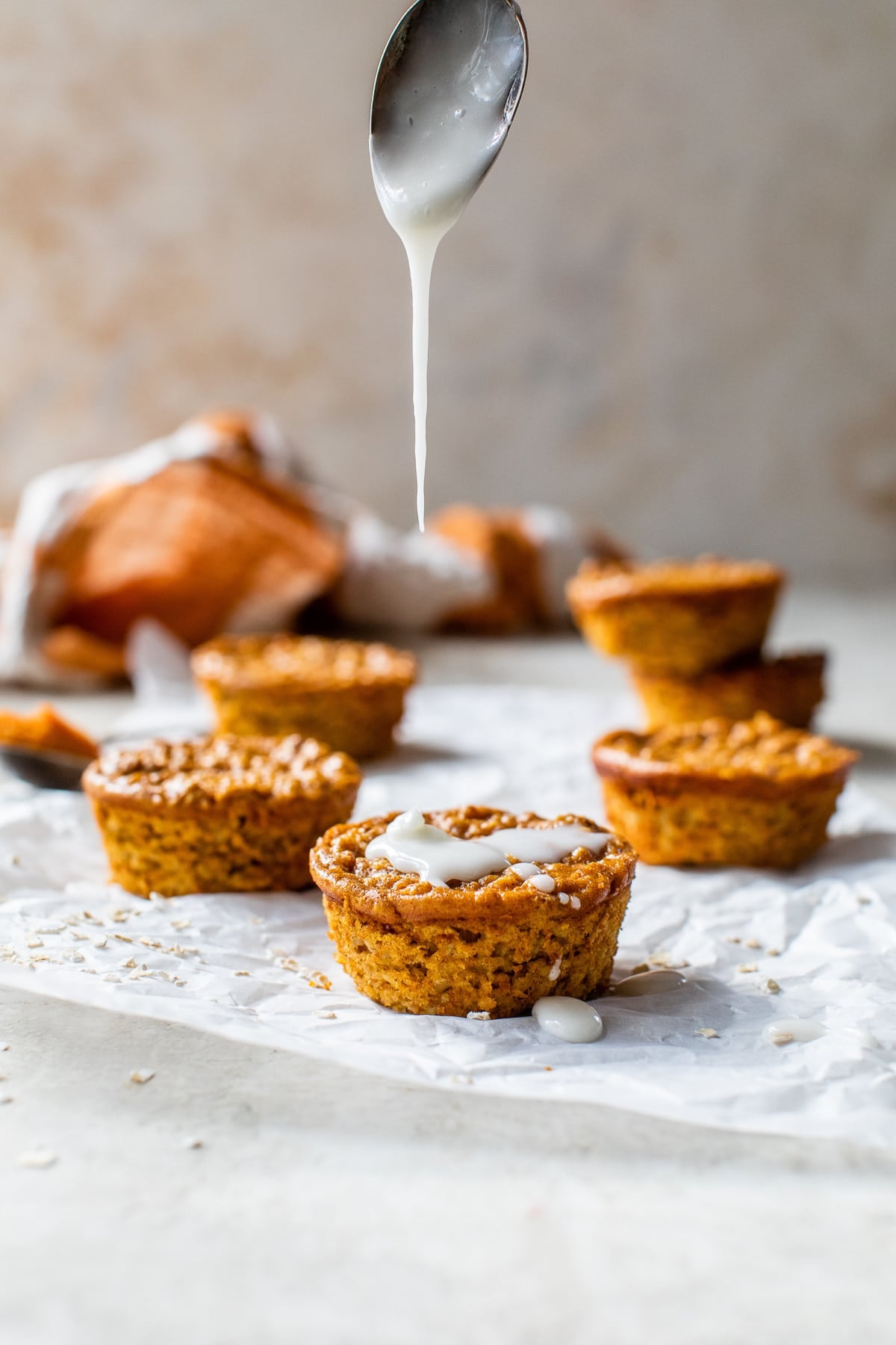 Made with pumpkin puree, oats, pumpkin pie spice, and yogurt, these Pumpkin Baked Oatmeal Cups are an easy breakfast full of fall flavor. Glaze being drizzled over baked pumpkin oatmeal cups