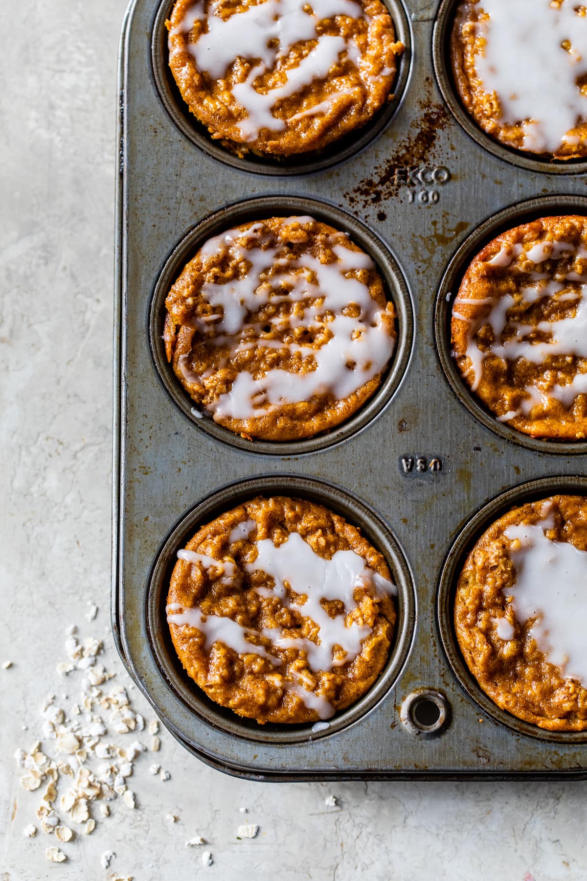 Made with pumpkin puree, oats, pumpkin pie spice, and yogurt, these Pumpkin Baked Oatmeal Cups are an easy breakfast full of fall flavor. Pumpkin Baked Oatmeal Cups topped with glaze in a muffin pan