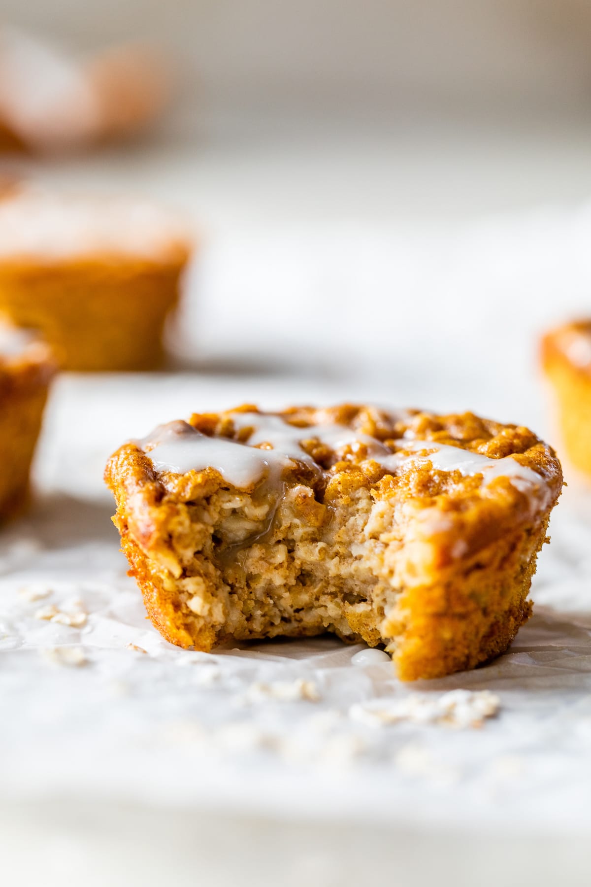 A pumpkin baked oatmeal cup on the counter with a bite missing to show the inside.