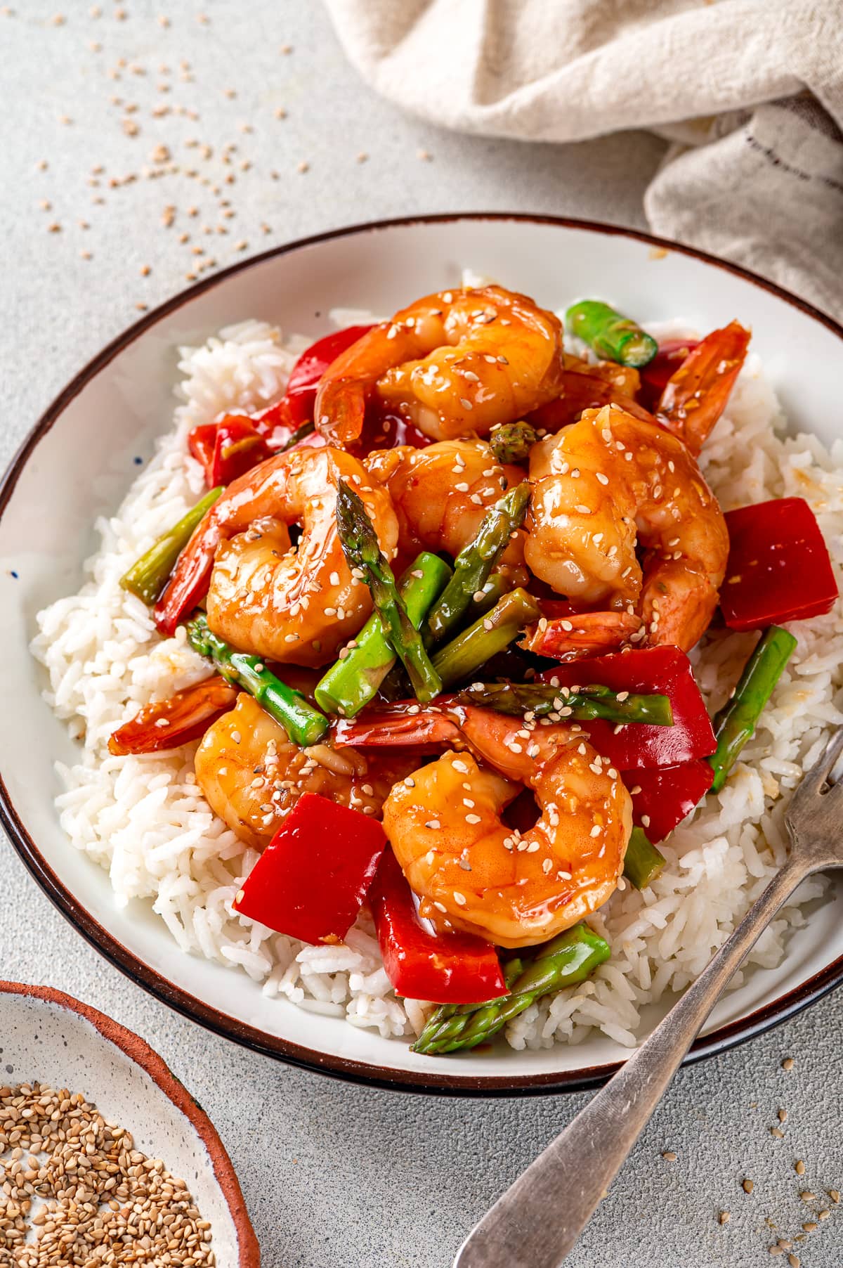 With juicy shrimp, asparagus, and red bell peppers, this Shrimp Stir Fry recipe makes a quick, easy, and healthy dinner in just 20 minutes! Shrimp and vegetables in a bowl over rice.