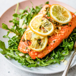 Baked Steelhead Trout with lemon and arugula on a plate