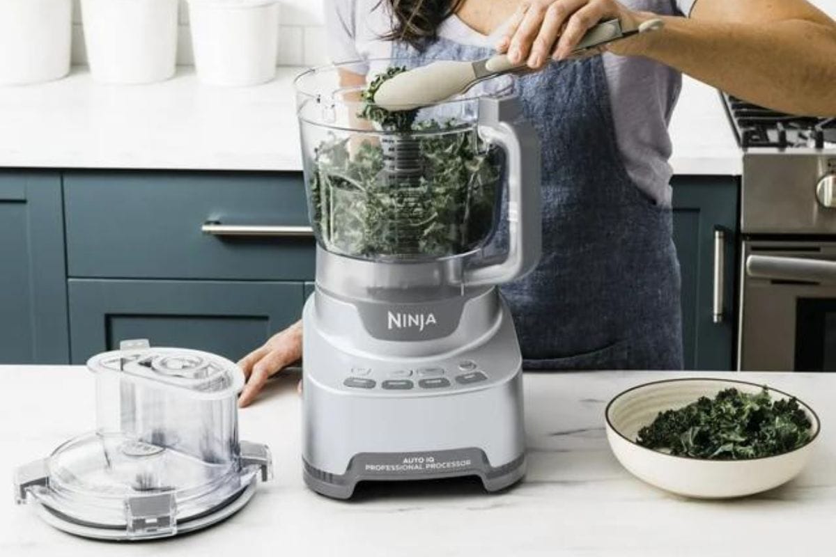 Someone putting kale into Ninja Professional XL Food Processor