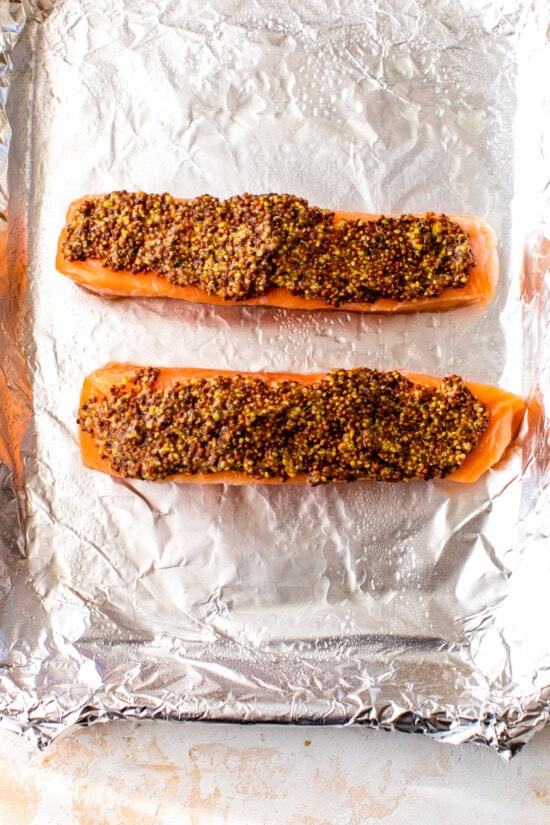 salmon with whole grain mustard on a baking sheet.
