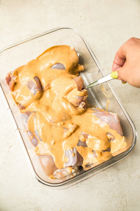 pouring yogurt marinade over the chicken.