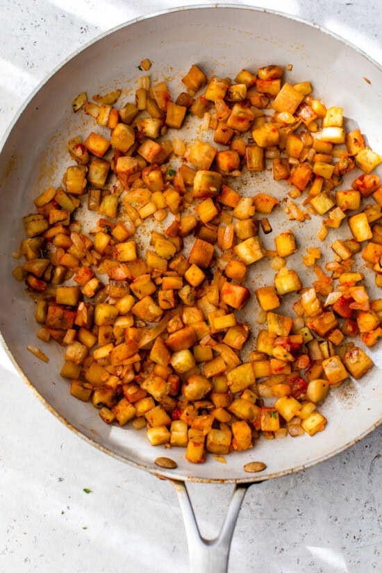 Peppers and zucchini in a skillet with eggplant and onion.