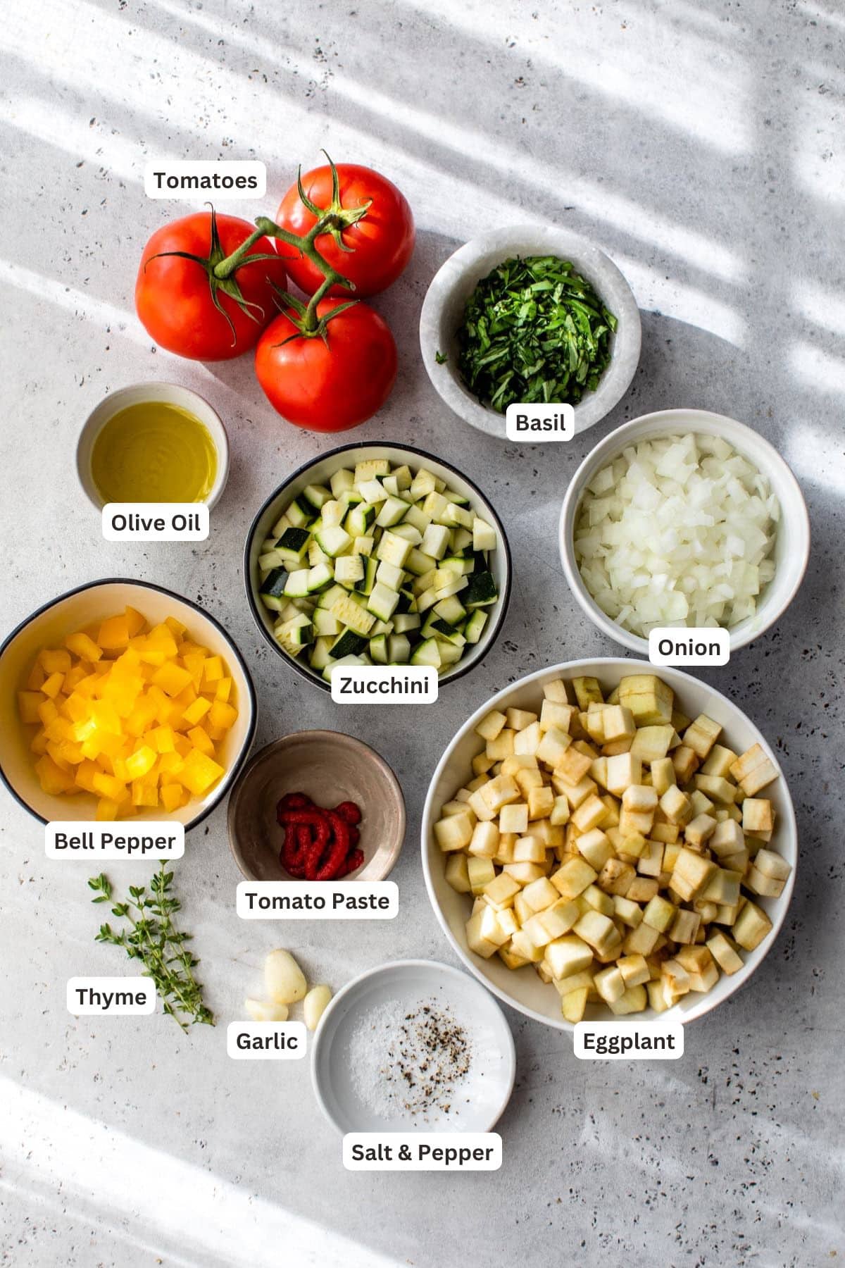 Ingredients for ratatouille on a marble counter.