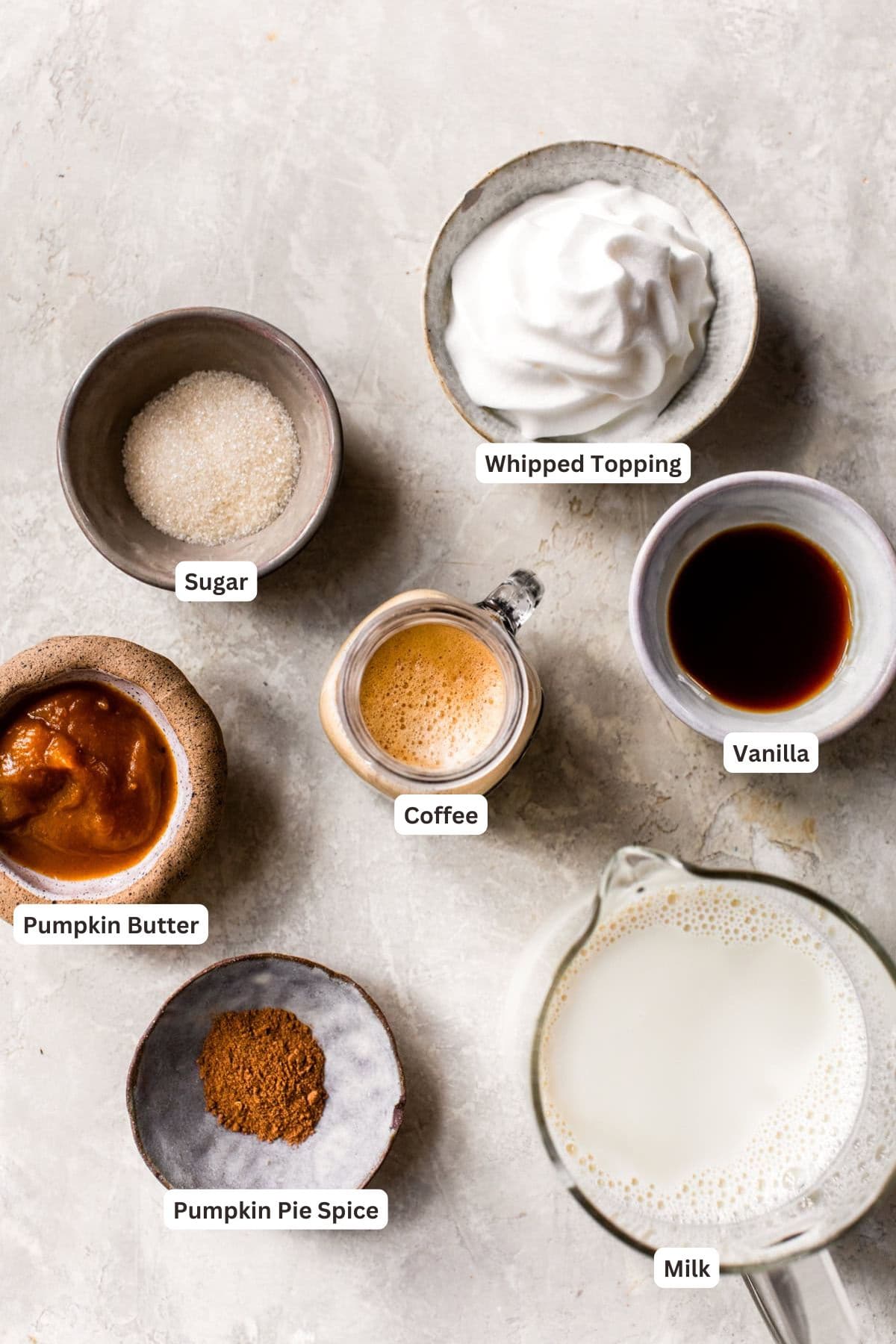 Pumpkin spice latte ingredients on a marble counter.