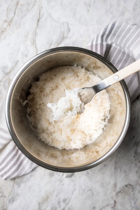 Jasmine rice is a fragrant rice perfect for pairing with curries and stir fries! Make it in the Instant Pot and it's easy, fluffy, and tasty. Forkful of jasmine rice held over pot