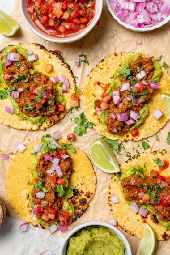 These vegan lentil tacos are easy to make, full of big Tex-Mex flavor and great for meal prep. Add your favorite toppings and dig in! Overhead view of vegan lentil taco filling on 4 charred corn tortillas