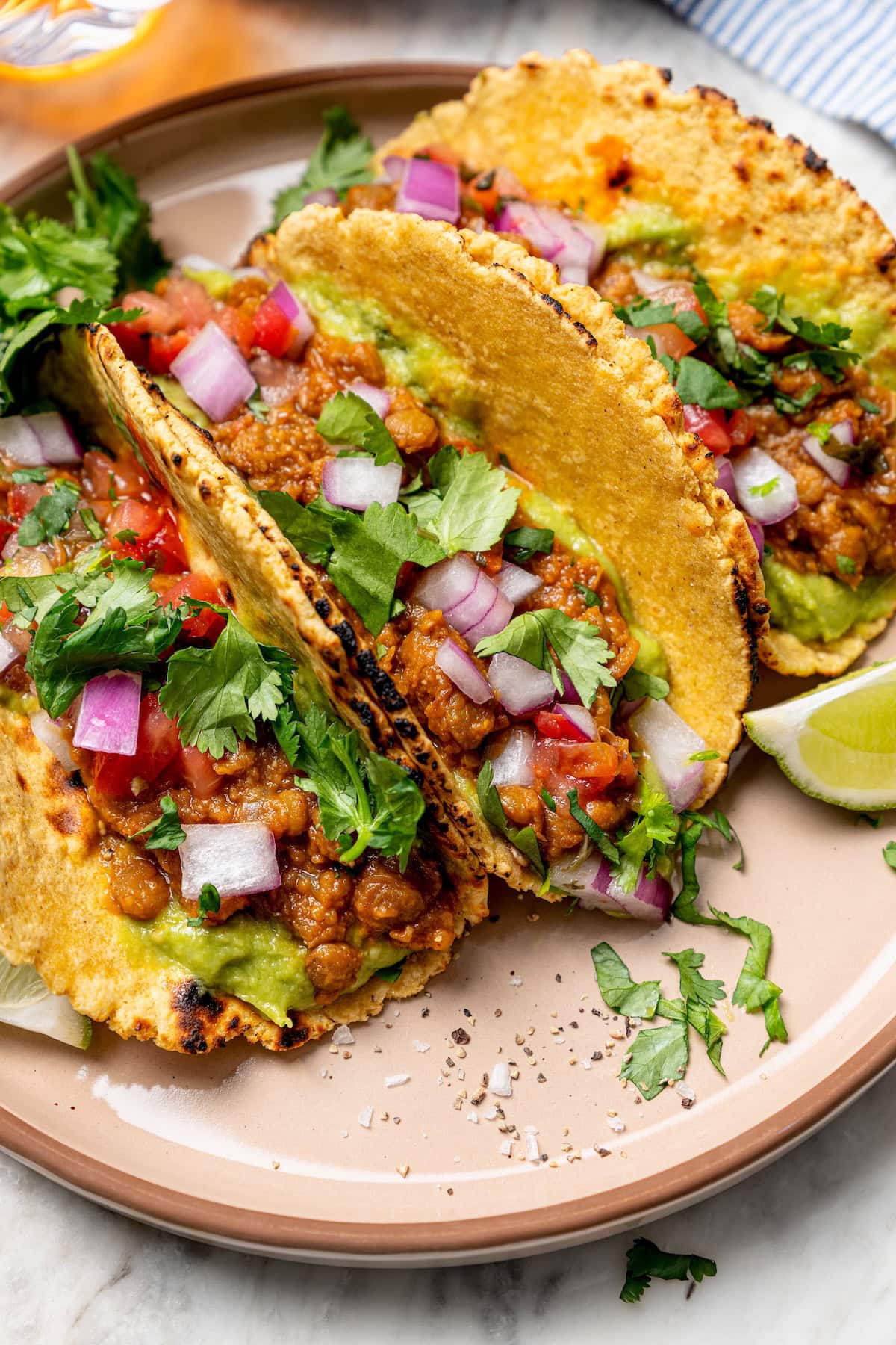 These vegan lentil tacos are easy to make, full of big Tex-Mex flavor and great for meal prep. Add your favorite toppings and dig in! 3 vegan lentil tacos on plate