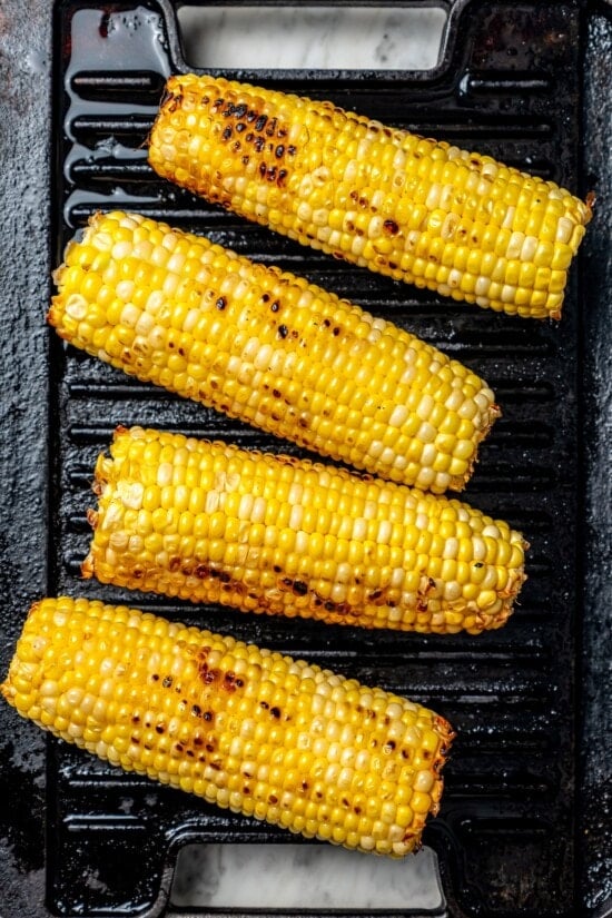 This lighter version of the classic grilled Mexican street corn recipe has all the flavor of the original, with mayo, cotija, lime and Tajín! Overhead view of corn on grill pan