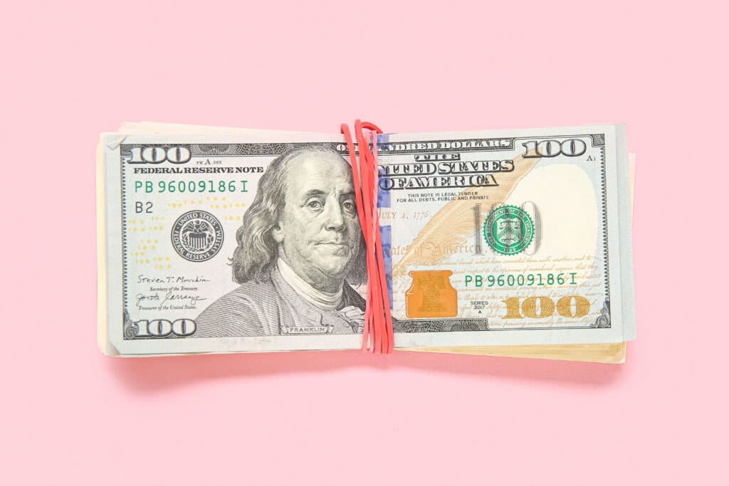 bundle of money and $100 bill on top for article ways to make more money when you're tired at the end of the day