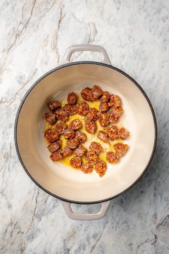 With spicy chorizo, potatoes, corn, crab, clams and shrimp, this seafood boil recipe is a complete meal in one pot. So easy to make too! Overhead view of chorizo cooking in Dutch oven