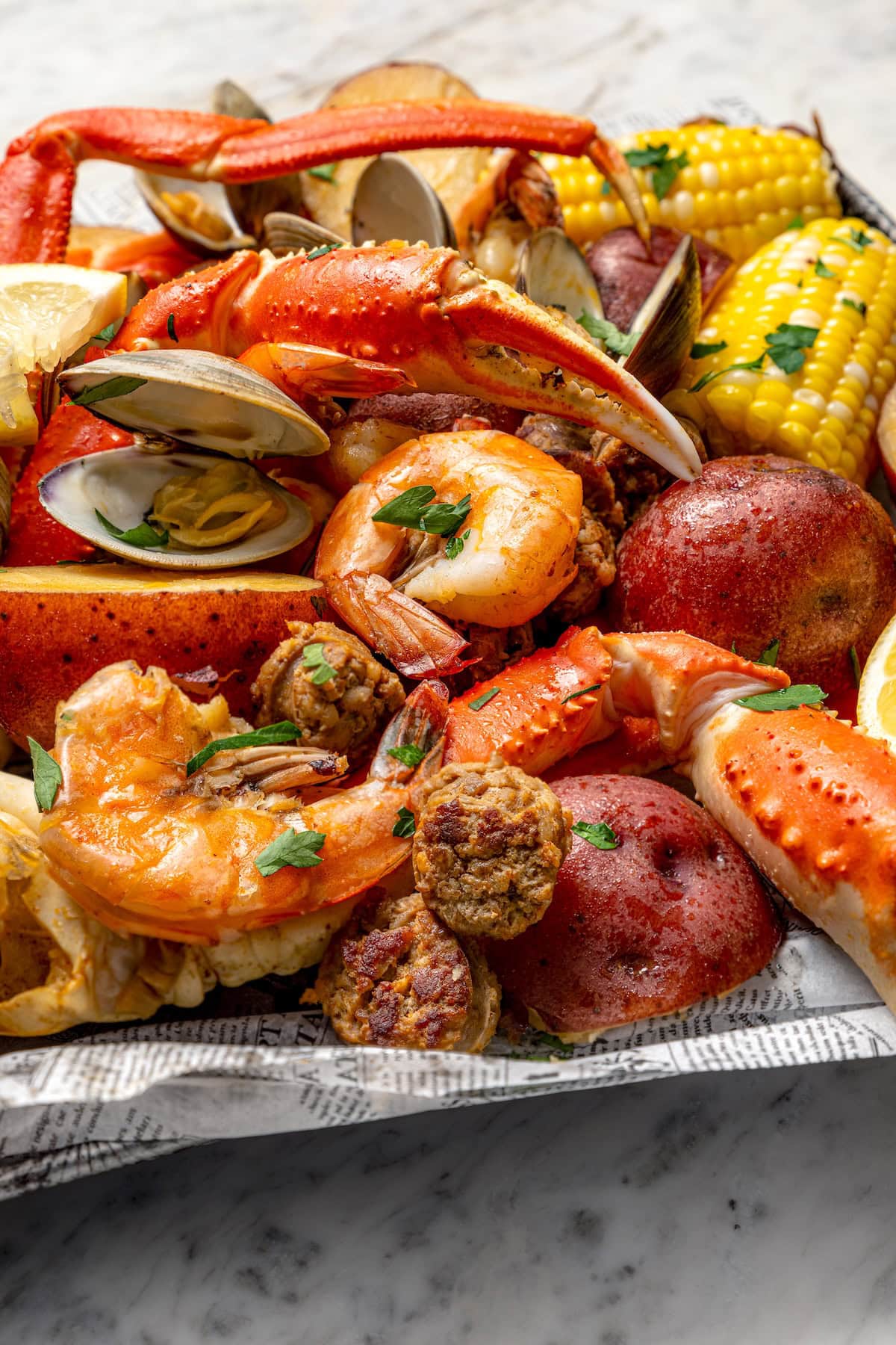 With spicy chorizo, potatoes, corn, crab, clams and shrimp, this seafood boil recipe is a complete meal in one pot. So easy to make too! Closeup of seafood boil with crab legs, chorizo, shrimp, and clams