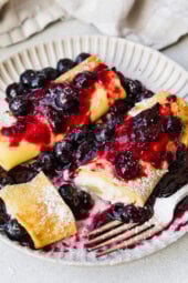 Cooked cheese blintzes on plate with blueberry sauce